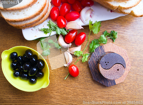 Image of top-view of a wood table with olives tomatoes bread