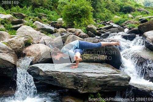 Image of Young fit woman doing yoga oudoors at waterfall