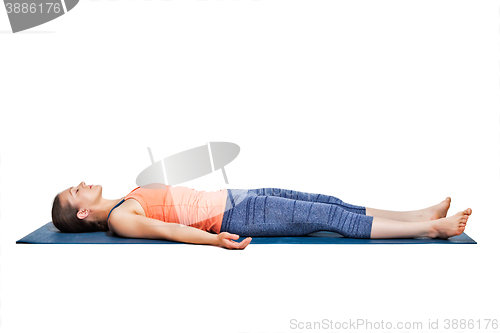 Image of Sporty woman relaxes in yoga asana Savasana