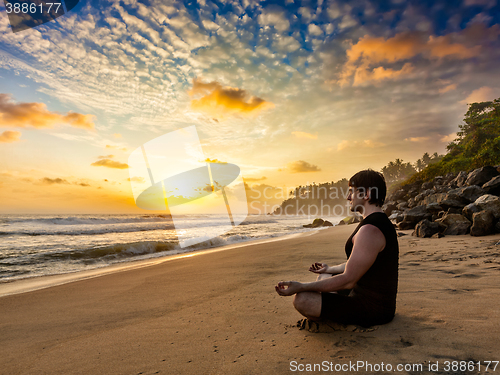 Image of Young fit man do yoga meditation on tropical beach