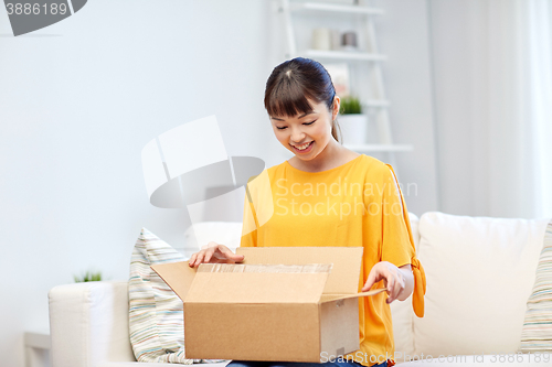 Image of happy asian young woman with parcel box at home