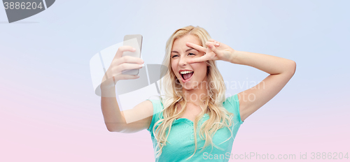 Image of smiling young woman taking selfie with smartphone