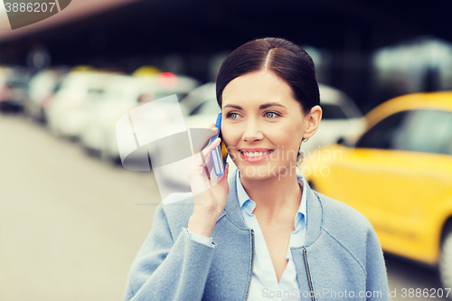 Image of smiling woman with smartphone over taxi in city