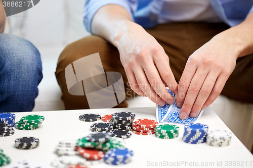 Image of close up of male hand with playing cards and chips