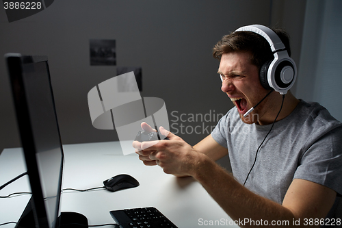 Image of man in headset playing computer video game at home