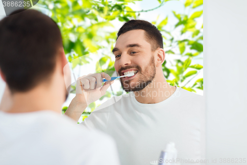 Image of man with toothbrush cleaning teeth at bathroom