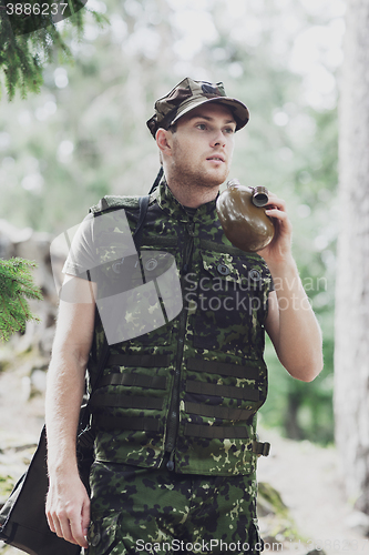 Image of young soldier with gun and flask in forest