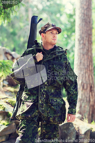 Image of young soldier or hunter with gun in forest