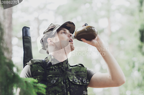 Image of young soldier with gun and flask in forest