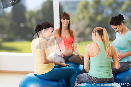 Image of happy pregnant women sitting on balls in gym