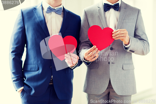 Image of close up of male gay couple holding red hearts