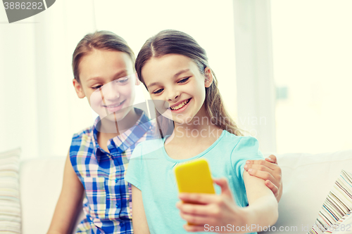 Image of happy girls with smartphone taking selfie at home