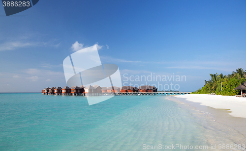 Image of bungalow huts in sea water on exotic resort beach