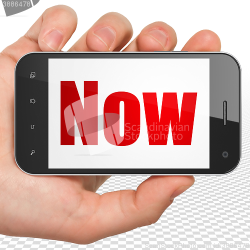 Image of Time concept: Hand Holding Smartphone with Now on display