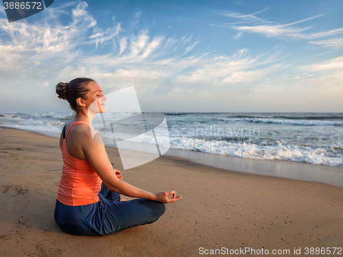 Image of Young sporty fit woman doing yoga oudoors at beach
