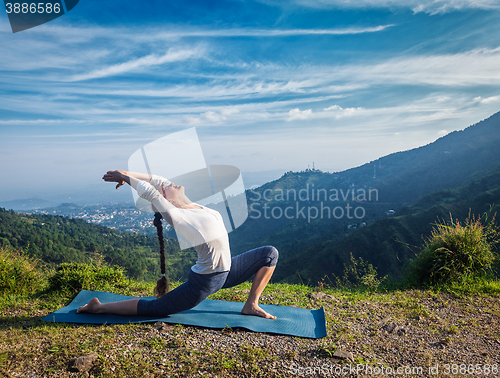 Image of Woman practices yoga asana Anjaneyasana outdoors