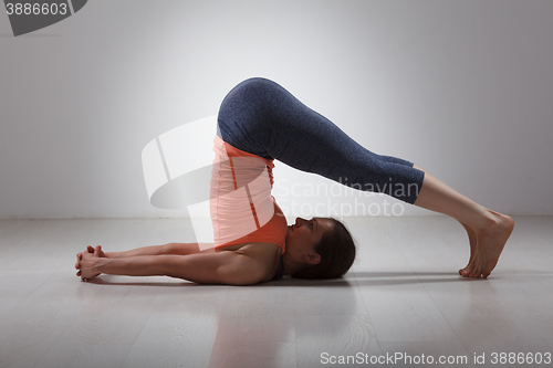 Image of Sporty woman practices yoga asana Halasana