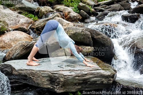 Image of Young fit woman doing yoga oudoors at waterfall