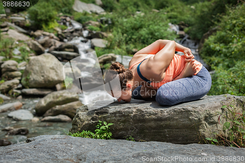 Image of Young woman does yoga oudoors at waterfall