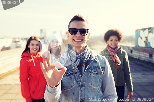 Image of happy teenage friends showing ok sign on street