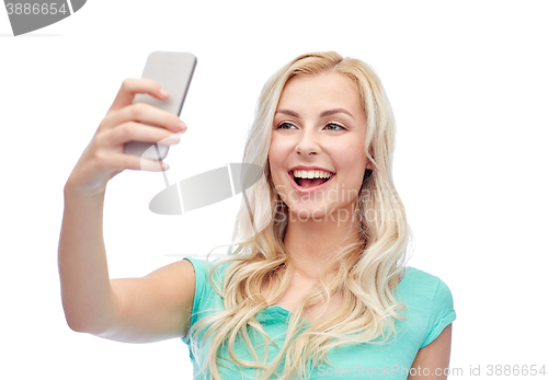 Image of smiling young woman taking selfie with smartphone