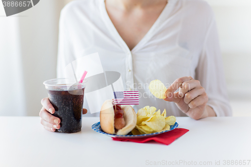 Image of close up of woman eating chips, hot dog and cola