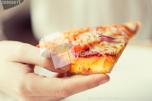 Image of close up of hand holding pizza slice