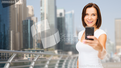 Image of woman taking picture by smartphone over dubai city