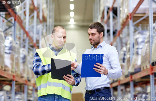 Image of worker and businessmen with clipboard at warehouse