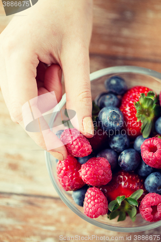 Image of close up of woman hands with berries in glass bowl