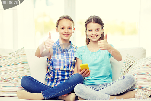 Image of happy girls with smartphone sitting on sofa