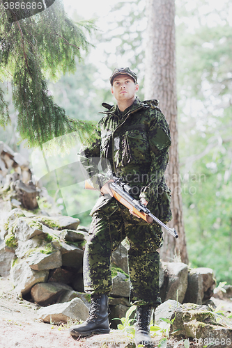 Image of young soldier or hunter with gun in forest