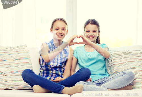 Image of happy little girls showing heart shape hand sign