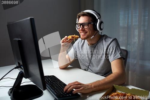 Image of man in headset playing computer video game at home