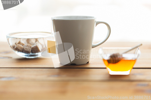 Image of close up tea cup with honey and sugar on table