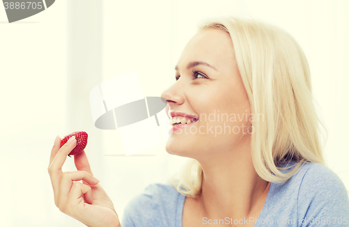 Image of happy woman eating strawberry at home