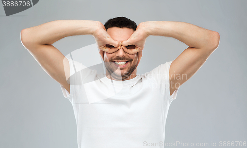 Image of man making finger glasses over gray background
