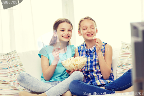 Image of happy girls with popcorn watching tv at home