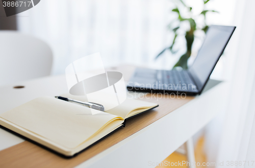 Image of notebook and laptop computer on office table