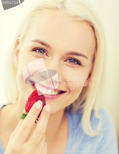 Image of happy woman eating strawberry at home