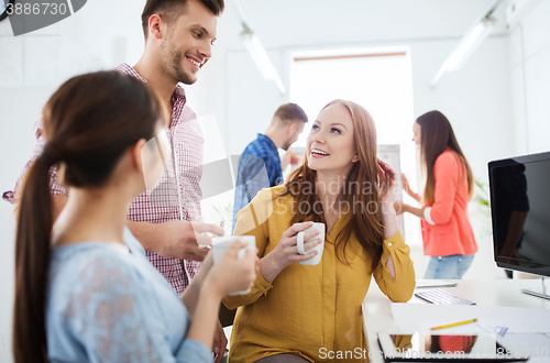 Image of happy creative team drinking coffee at office