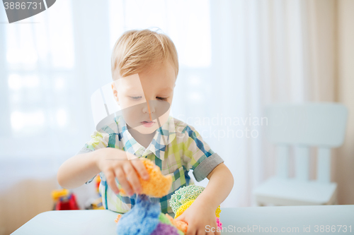 Image of happy little baby boy with ball clay at home