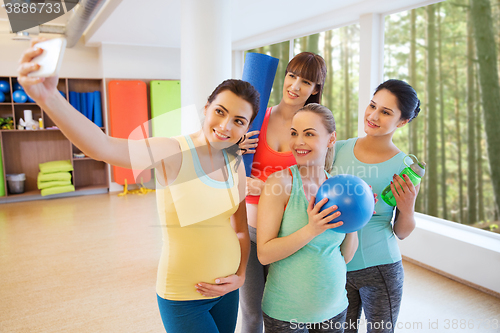 Image of pregnant women taking selfie by smartphone in gym