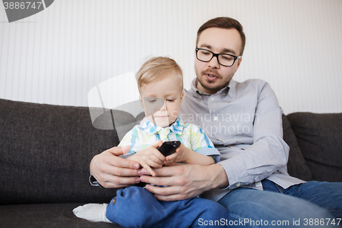 Image of father and son with remote watching tv at home