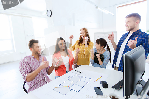 Image of happy creative team celebrating success at office