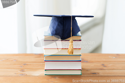 Image of close up of books and mortarboard on wooden table