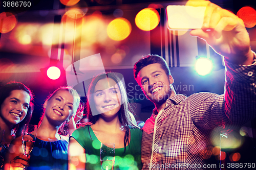 Image of friends taking selfie by smartphone in night club