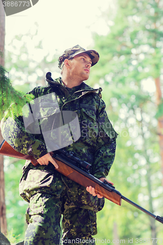 Image of young soldier or hunter with gun in forest