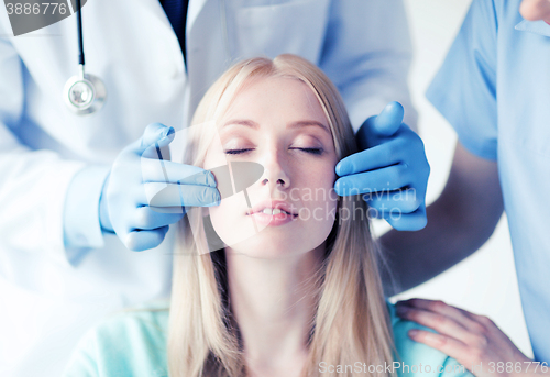 Image of plastic surgeon and nurse with patient