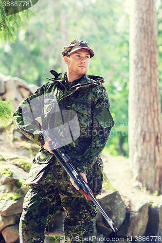 Image of young soldier or hunter with gun in forest